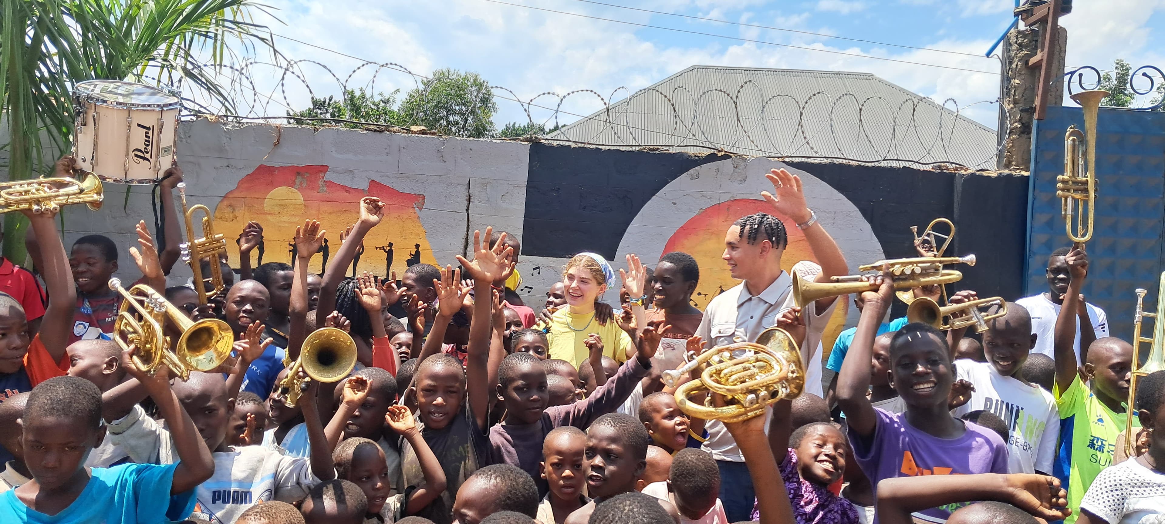 International volunteers with children of Saved By Music Foundation, all raising instruments