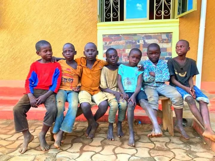 Children sitting quietly outside the foundation, some barefoot