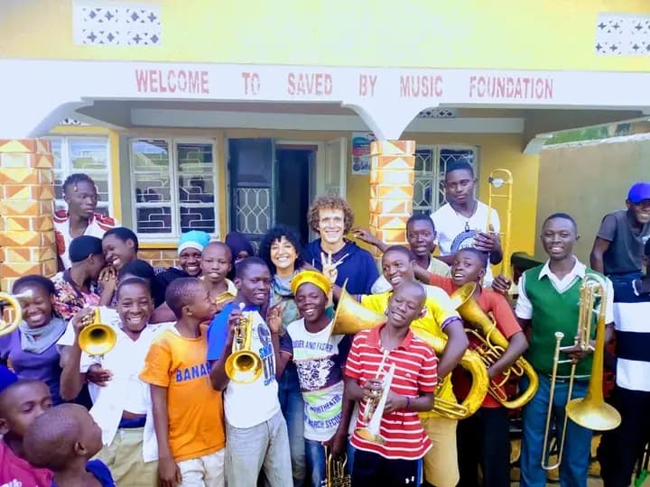 Volunteers and children in front of Saved By Music Foundation